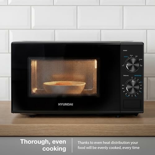 Black microwave on a wooden counter with food inside.