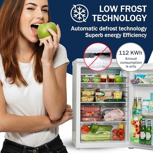 Woman eating apple near open fridge with low frost technology