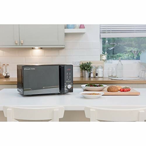 Microwave on kitchen counter with bowls and bread