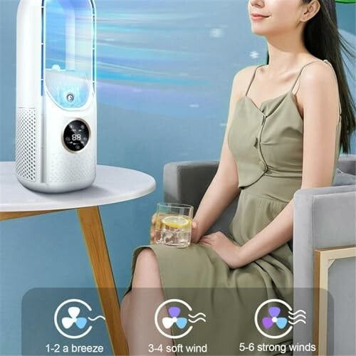 Woman sitting next to a portable air cooler with wind speed options.
